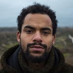 Portrait of a man with a beard outdoors in a winter landscape, conveying a moody atmosphere.